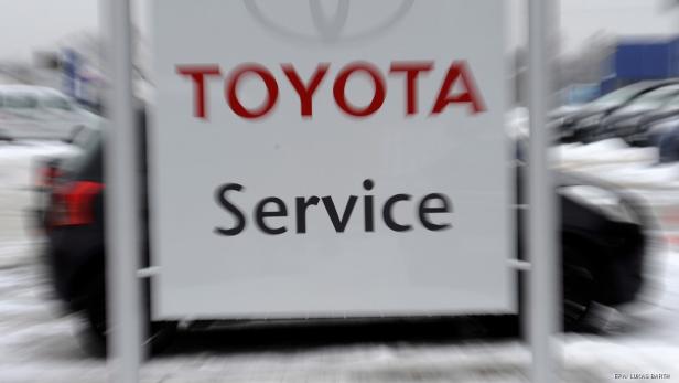 Ein Schild mit der Aufschrift „Toyota Service“ vor einem Autohaus im Winter.