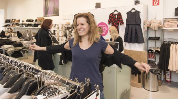 Eine Frau probiert in einem Bekleidungsgeschäft eine Jacke an.