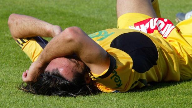 Ein Fußballspieler liegt erschöpft auf dem Rasen.