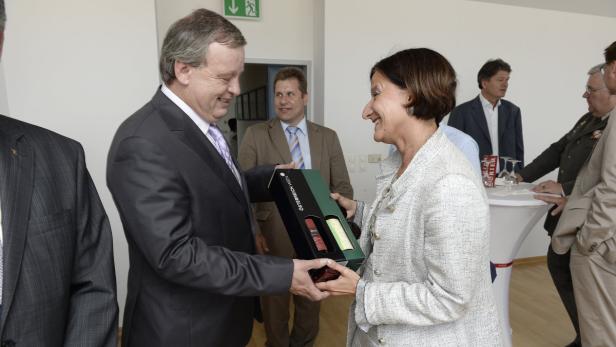 Ein Mann überreicht einer Frau eine Geschenkpackung mit österreichischem Wein.