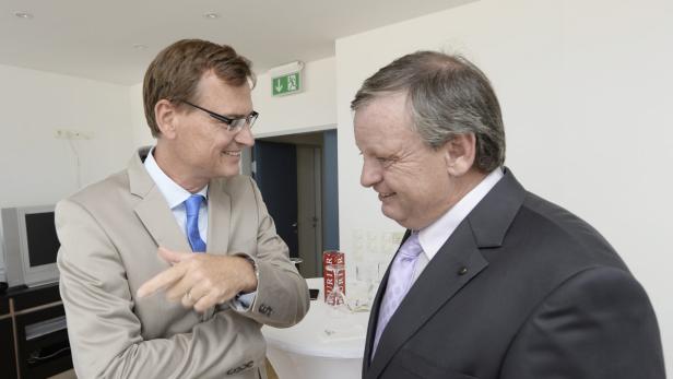 Zwei Männer in Anzügen unterhalten sich lächelnd.