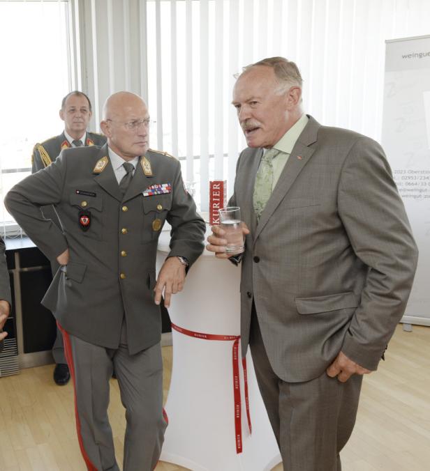 Ein Mann in Uniform und ein Mann im Anzug unterhalten sich bei einer Veranstaltung.