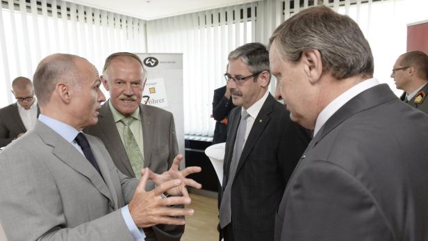 Eine Gruppe von Männern in Anzügen unterhält sich in einem Raum.