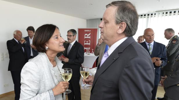 Eine Frau und ein Mann unterhalten sich bei einem Empfang mit Weingläsern in der Hand.