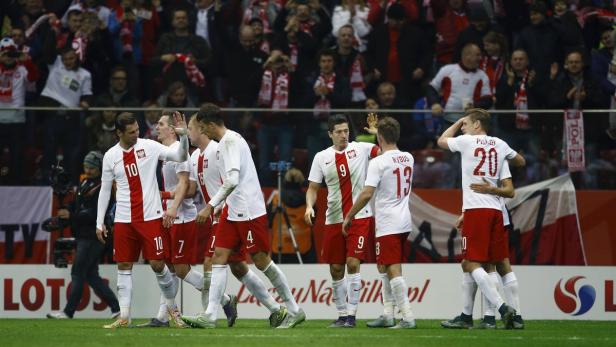 Polnische Fußballspieler feiern auf dem Spielfeld vor den jubelnden Zuschauern.