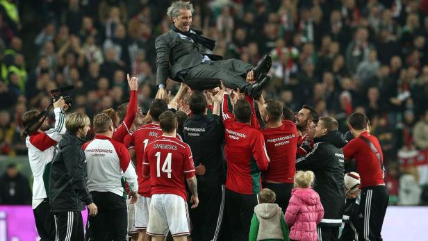Ungarische Fußballspieler feiern ihren Trainer, den sie in die Luft werfen.
