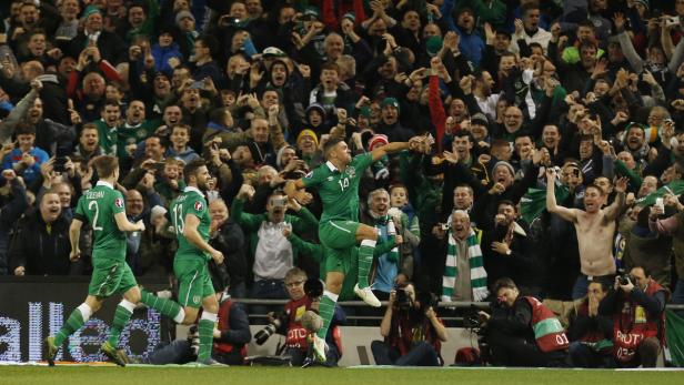 Irische Fußballspieler jubeln vor einer jubelnden Menschenmenge.
