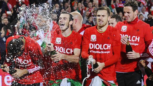 Walisischer Fußballspieler feiern mit Champagner.