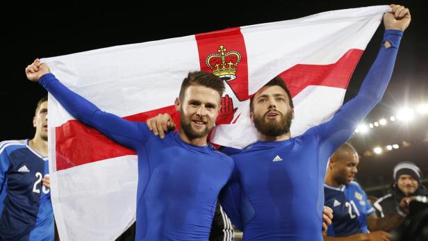 Zwei Fußballspieler feiern mit der nordirischen Flagge.