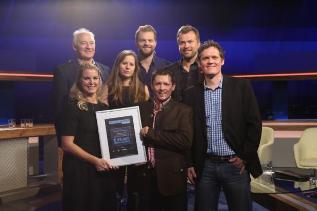 Eine Gruppe von Personen posiert mit einer Urkunde über 25.000 Euro.