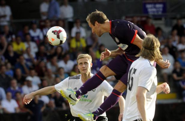 Ein Fußballspieler springt, um den Ball mit dem Kopf zu spielen, während andere Spieler zusehen.