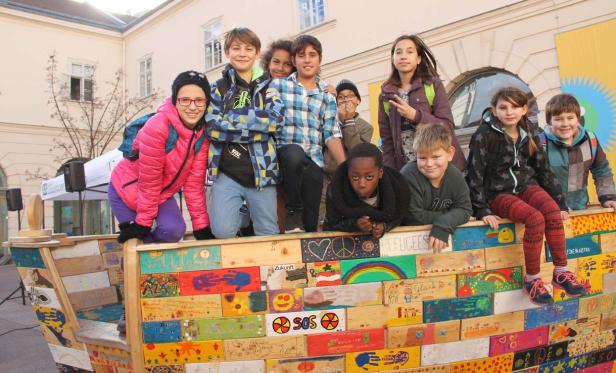 Eine Gruppe von Kindern steht auf einem bemalten Holzboot.