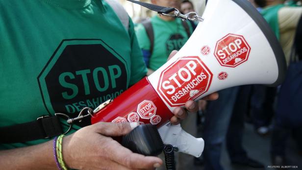 Eine Person hält ein Megafon mit der Aufschrift „Stop Desahucios“.