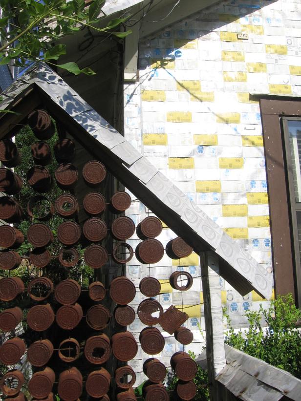 Ein Haus mit einer Fassade aus Bierkartons und einer Dekoration aus rostigen Dosen.