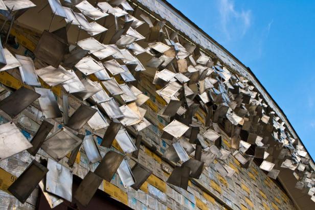 Eine Fassade, die mit alten Dosen und Metallplatten verziert ist.