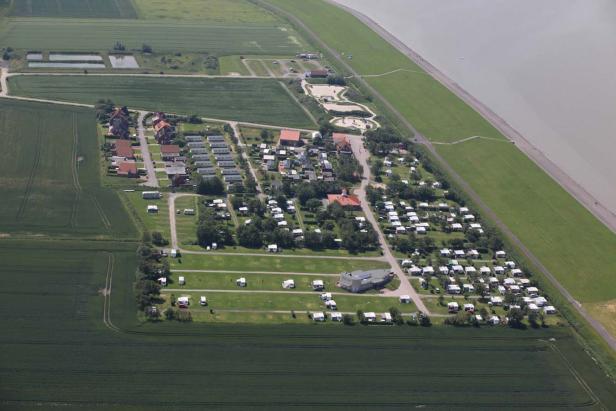 Luftaufnahme eines Campingplatzes mit Wohnwagen und Zelten in Küstennähe.