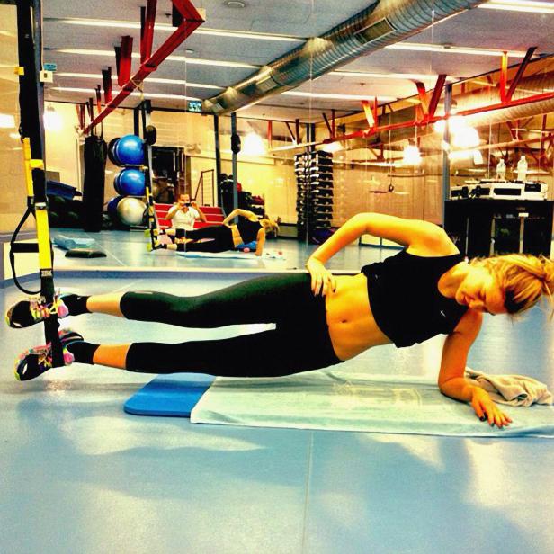 Eine Frau macht im Fitnessstudio einen seitlichen Unterarmstütz.