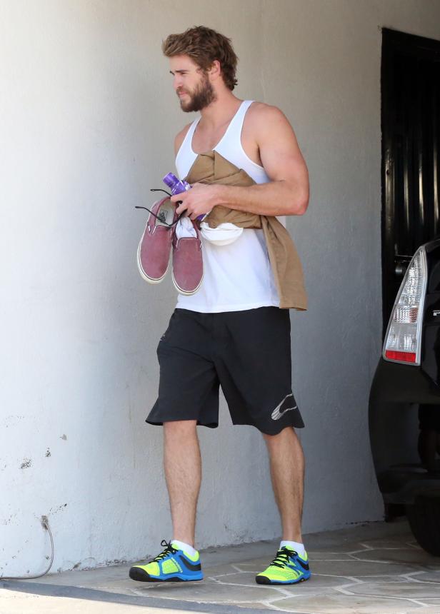 Liam Hemsworth in Sportkleidung trägt Schuhe und eine Trinkflasche.