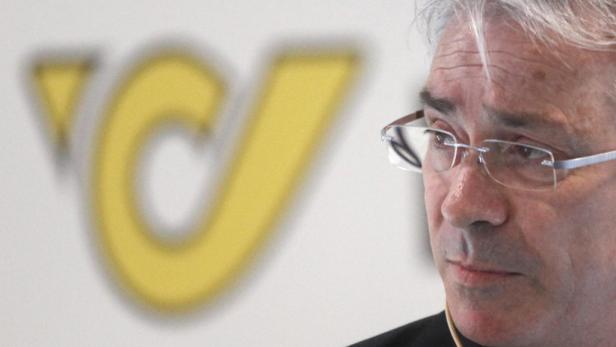 Post-General Georg Pölzl Ein Mann mit Brille vor dem Logo der Deutschen Post.