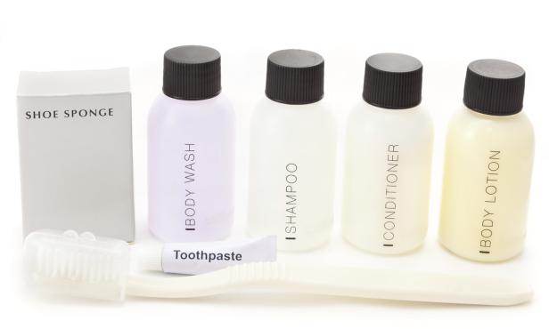 Ein Set mit kleinen Reiseartikeln, darunter Shampoo, Duschgel, Zahnpasta und eine Schuhbürste.