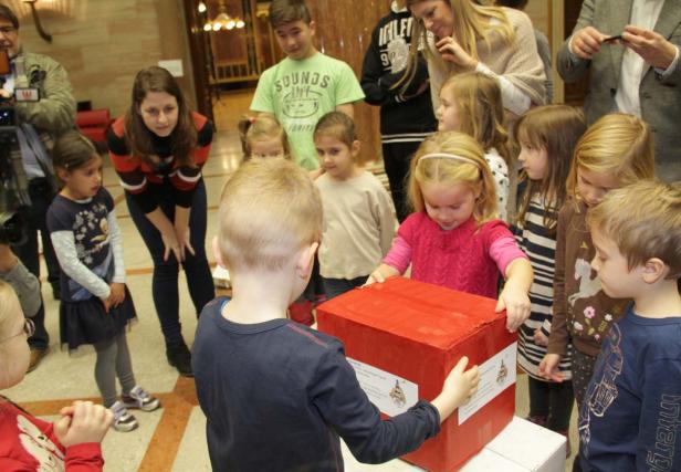 Eine Gruppe von Kindern steht um einen großen, roten Karton.