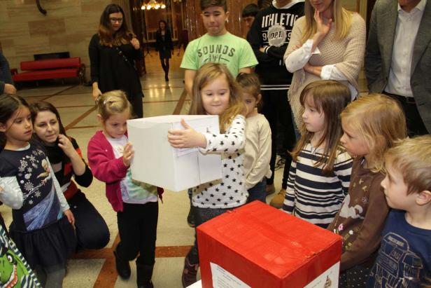 Eine Gruppe von Kindern steht um zwei Kisten herum.