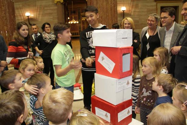 Eine Gruppe Kinder und Erwachsene steht um einen Turm aus rot-weißen Kisten.
