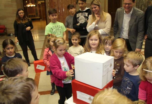 Eine Gruppe von Kindern steht um einen Stapel von rot-weißen Geschenkkartons.