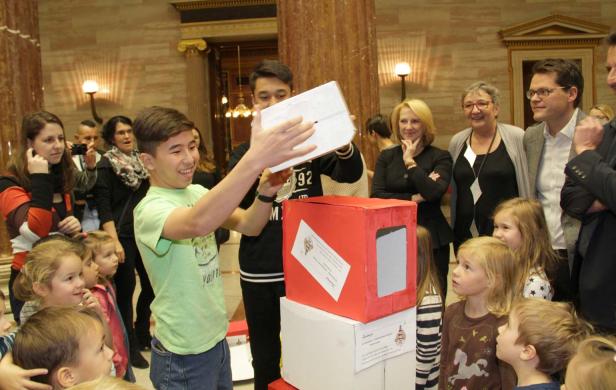 Eine Gruppe von Kindern und Erwachsenen steht um einen Turm aus Kartons herum.