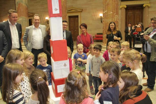 Eine Gruppe Kinder steht um einen Turm aus roten und weißen Kisten herum.