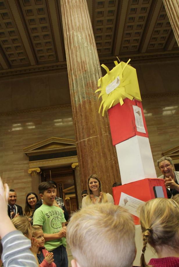 Eine Gruppe von Kindern steht vor einem hohen, selbstgebauten Turm aus Kartons.