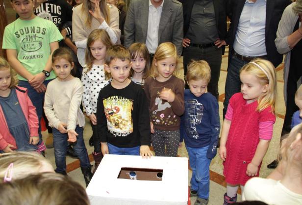 Eine Gruppe von Kindern steht um eine Wahlurne.