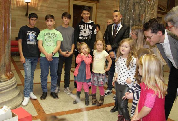 Eine Gruppe von Kindern und Erwachsenen steht in einem Gebäude mit Marmorsäulen.