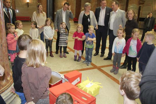 Eine Gruppe Kinder und Erwachsene steht um eine Ansammlung von bemalten Kartons herum.