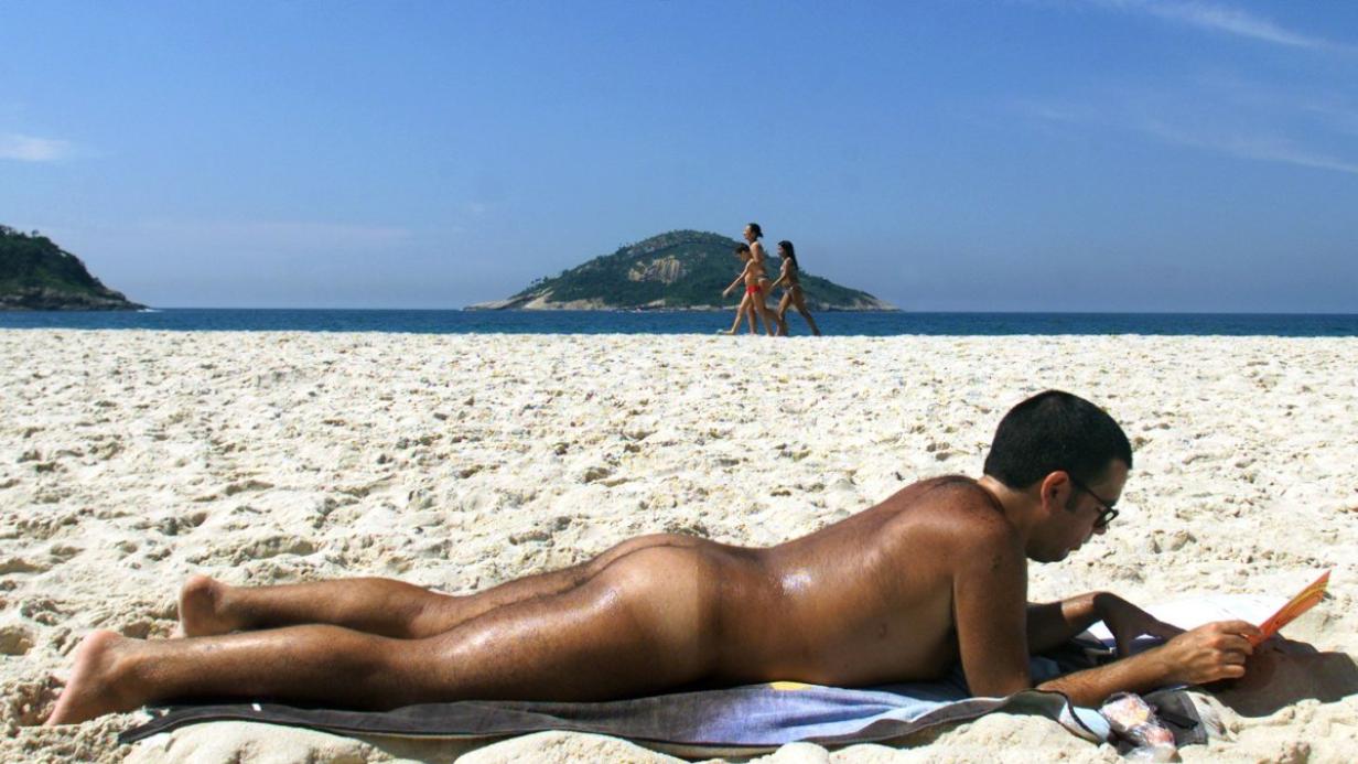 A Brazilian nudist reads a book at Abrico beach in Rio de Janeiro.