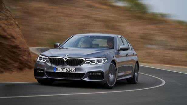 Ein grauer BMW fährt auf einer kurvigen Straße.