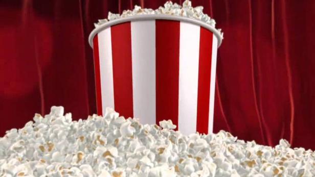 Ein rot-weiß gestreifter Popcorn-Eimer steht vor einem roten Vorhang.