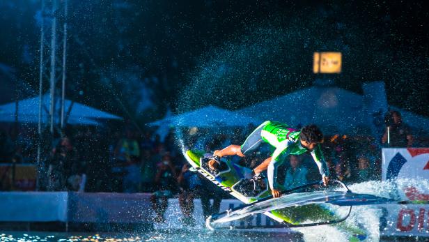 Ein Windsurfer springt mit seinem Board über das Wasser.