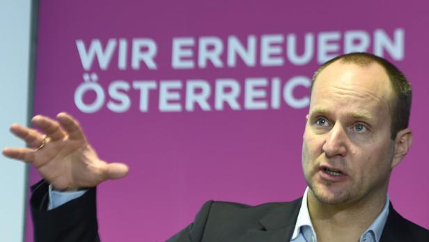 Ein Mann gestikuliert vor einem lilafarbenen Hintergrund mit der Aufschrift „Wir erneuern Österreich“.