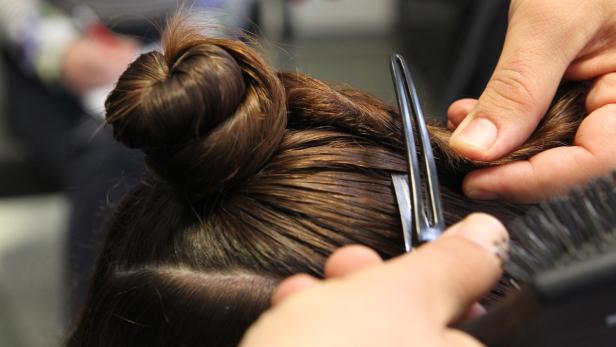 Ein Friseur steckt eine Hochsteckfrisur mit einer Haarnadel fest.