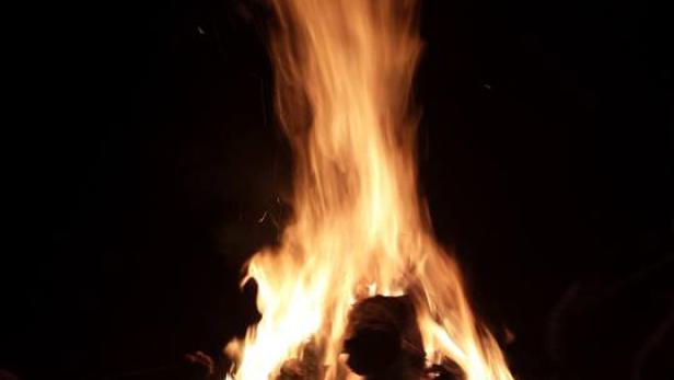 Ein großes Lagerfeuer brennt in der Dunkelheit.