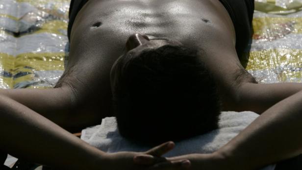 A man sunbathes on a beach in Hong Kong October 26, 2007. A growing trend in East Asia to soak up the sun either on beaches or in tanning salons is worrying dermatologists in the region who say they are seeing a rise in skin cancer, which is caused by cumulative over-exposure to the sun. Picture taken October 26, 2007. To match feature CANCER-SKIN/ASIA REUTERS/Bobby Yip (CHINA)