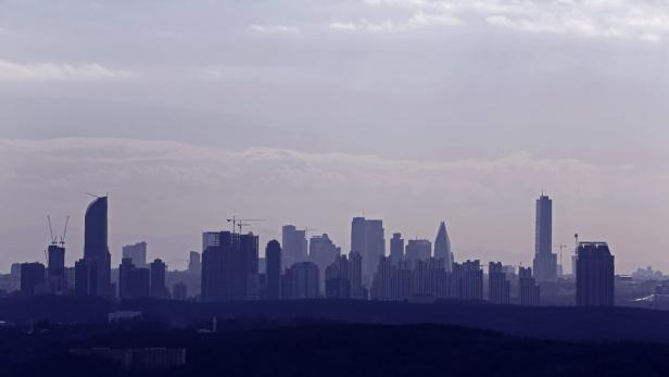 Die Skyline einer Stadt erstreckt sich unter einem bewölkten Himmel.