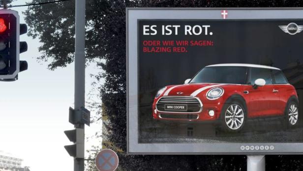 Eine rote Ampel neben einer Mini Cooper Werbung, die besagt: „Es ist rot“.