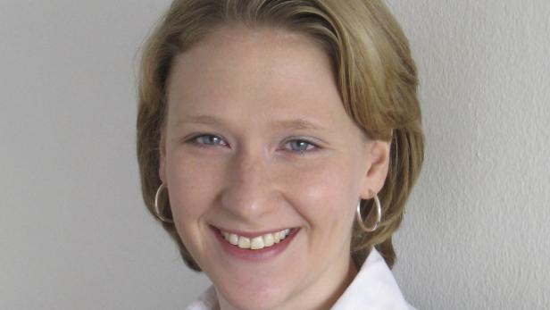 Eine lächelnde Frau mit blonden Haaren und Ohrringen.