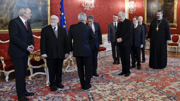 Eine Gruppe von Männern unterschiedlicher Glaubensrichtungen steht in einem opulenten Raum.