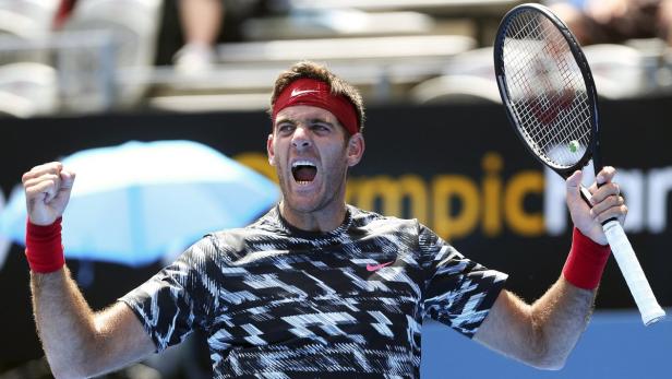 Ein Tennisspieler mit rotem Stirnband jubelt mit erhobener Faust und Tennisschläger.