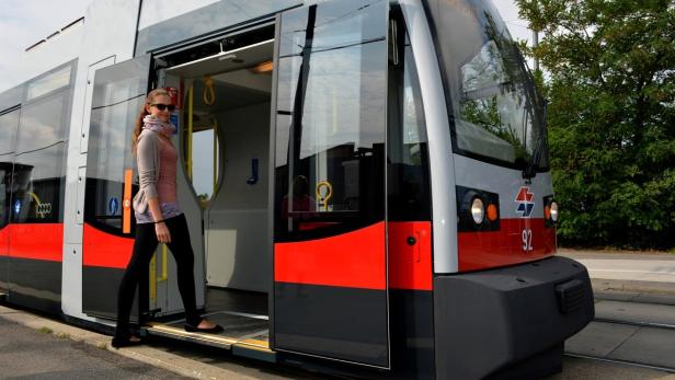 Eine junge Frau steigt in eine moderne Straßenbahn ein.