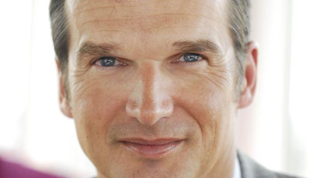 Porträt eines Mannes mit blauen Augen und grau meliertem Haar.
