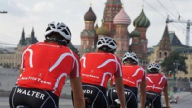 Eine Gruppe Radfahrer des Austria Teams fährt vor dem Hintergrund der Basilius-Kathedrale in Moskau.